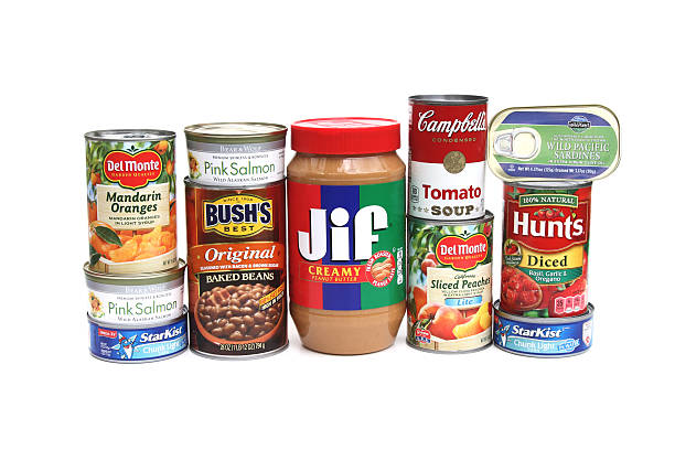 West Palm Beach, USA - October 8, 2014:  A studio shot of an assortment of canned foods. Foods include Campbell's tomato soup, Bush's baked beans, Del Monte peaches and mandarin oranges,  Chicken of the Sea tuna, Hunts diced tomatoes, Wild Planet sardines, Jif peanut butter, and Bear and Wolf salmon. Items are basic grocery staples found in many American kitlchens.