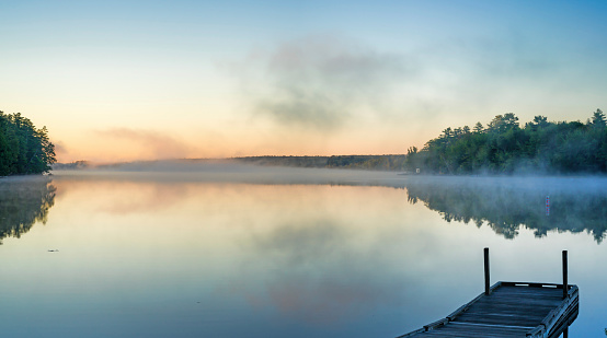 Toddy Pond, Maine, in the early morning light with reflected mist above the water and a small boat dock in the foreground.