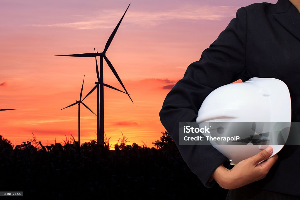 Engineer Engineer holding white helmet for workers security with wind turbine on background Adult Stock Photo