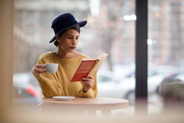 istock Young woman reading a book in a cafe. 518114930