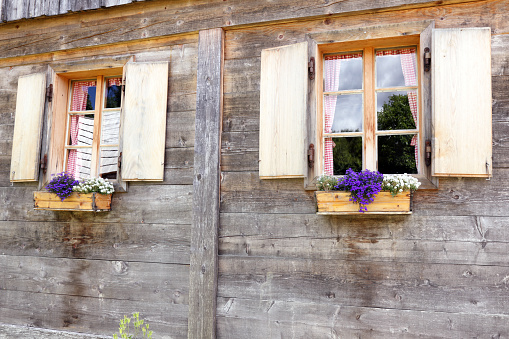 Old windows with flowers at wooden house