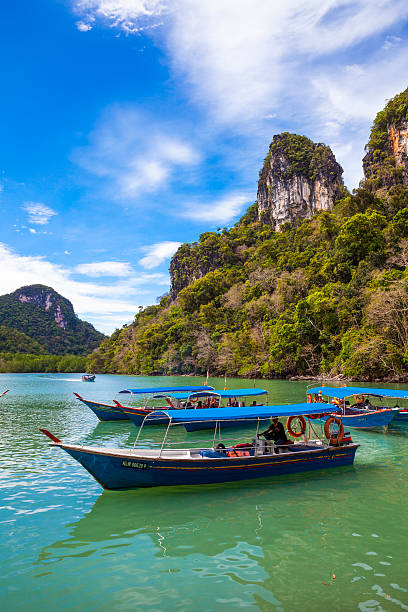Langkawi, Malaysia - March 9, 2011: Boat drivers patiently waiting for passengers in Langkawi, Malaysia. The lush forage of the islands can be seen in the background.