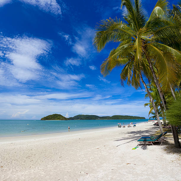 Langkawi, Malaysia - March 9, 2011: One of the beaches in Langkawi, Malaysia. People can be seen sunbathing and playing in the water. Other islands can be seen in the background.