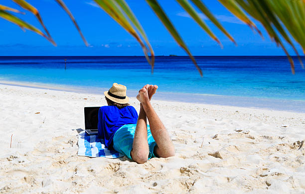 istock man with laptop on tropical beach 518117498