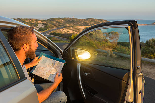 istock Young man in a car check directions on road map 518117556