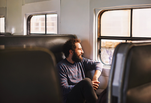 Shot of a young man sitting on the train during his morning commute