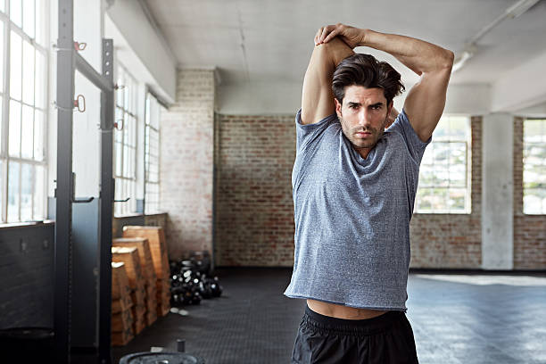 Stay supple, stay healthy Shot of a young man stretching before working out in the gym handsome people stock pictures, royalty-free photos & images