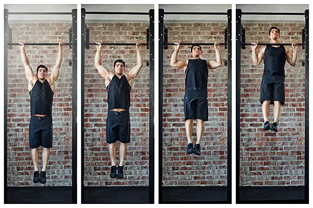 Shot of a young man doing pull ups in a gym