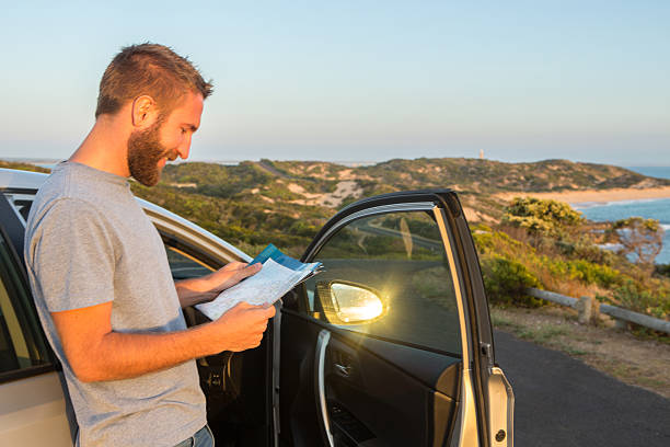 istock One young man reading map beside vehicle 518122428