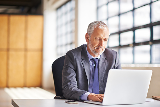 Cropped shot of a mature businessman working on his laptop in the office