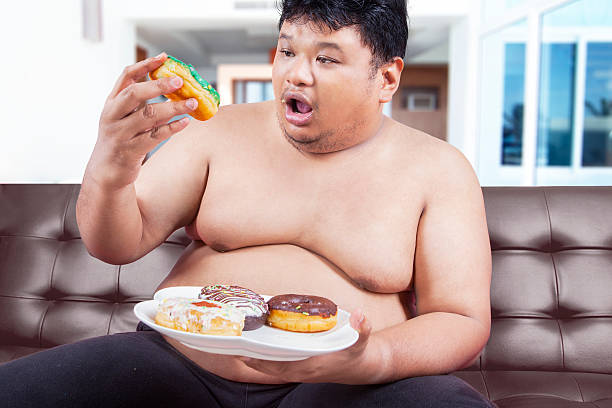 istock Overweight person eating donuts 518139986