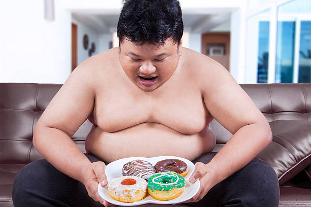 istock Hungry overweight man holding donuts 518140470