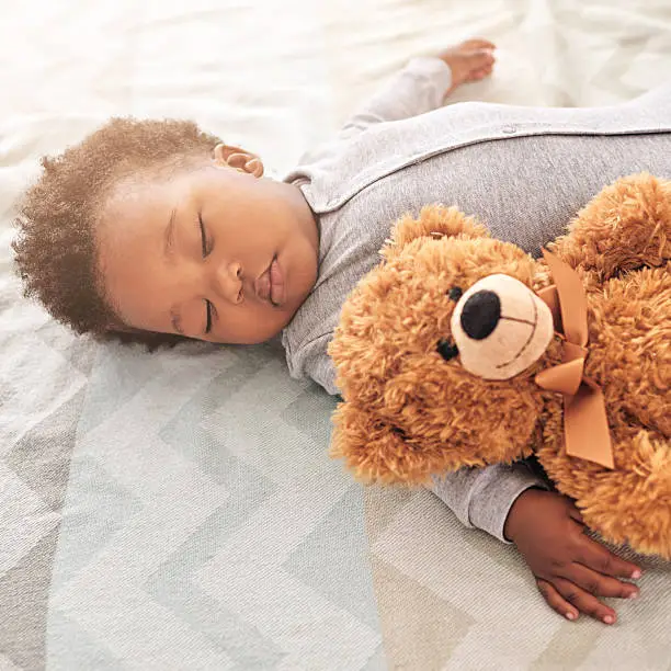 Shot of a little baby boy sleeping on a bed with a teddy bear