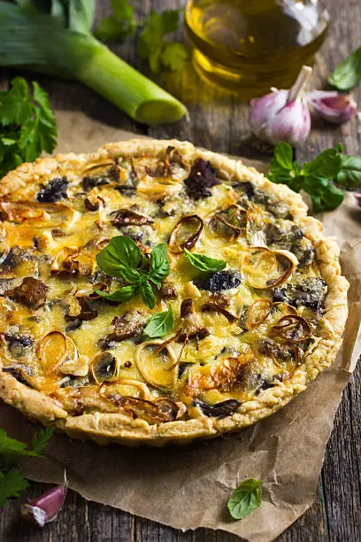 quiche with mushrooms, leek and cheese on rustic background