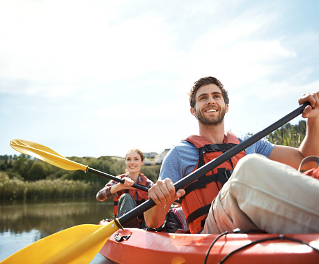 Shot of a young couple kayaking together on a lake