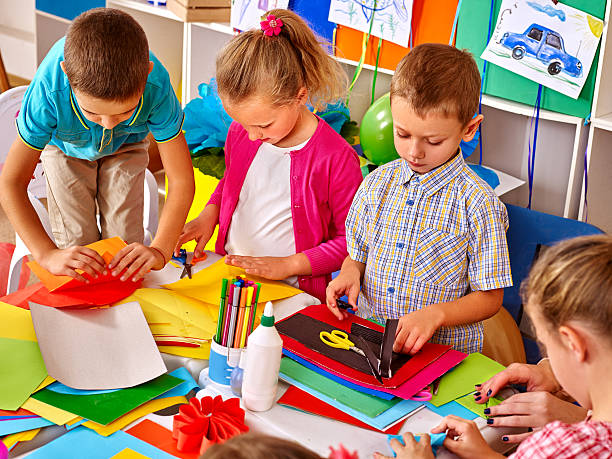 istock Kids holding colored paper on table in kindergarten 518147900