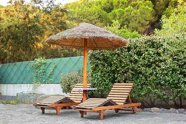 istock Wooden deck chairs under a straw umbrella 518149285