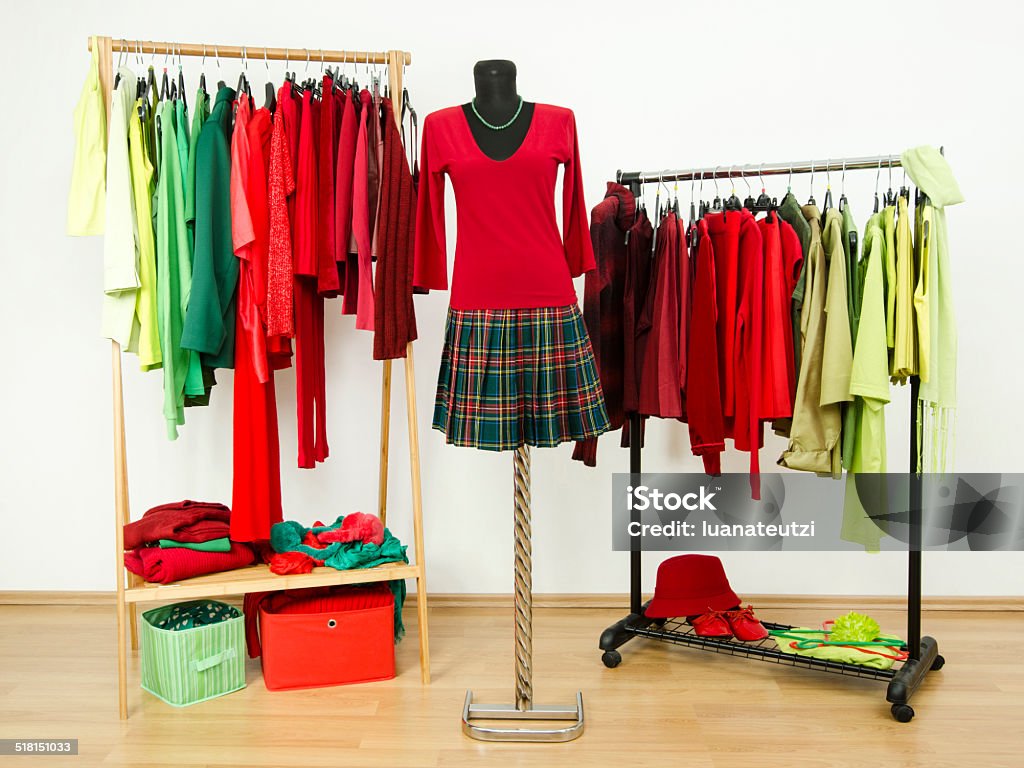 Wardrobe with complementary colors red and green clothes on hangers. Dressing closet full of all shades of green and red clothes and accessories and a plaid outfit on a mannequin. Arranging Stock Photo