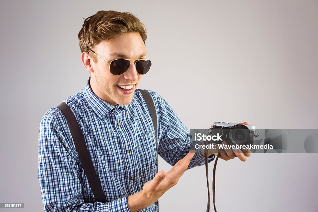 Geeky hipster holding a retro camera Geeky hipster holding a retro camera on grey background 20-29 Years Stock Photo
