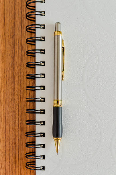 istock White diary and gold pen on wood background 518151701