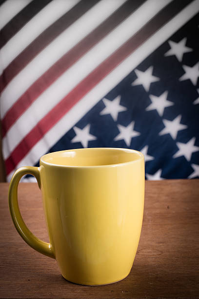 istock Yellow coffee cup on wooden table with USA flag background. 518172525