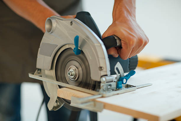 Carpenter Using His Circular Saw. Carpenter using circular saw in his workshop to cut plank. Closeup shot. circular saw stock pictures, royalty-free photos & images