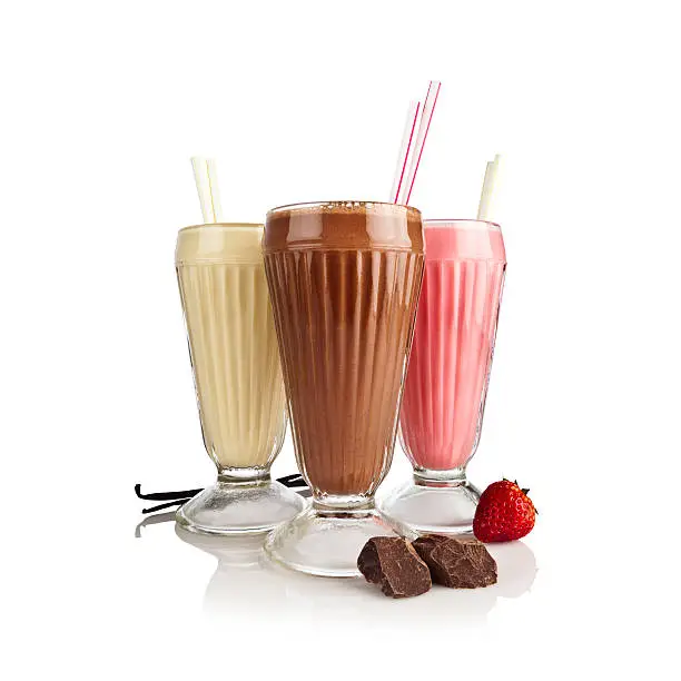 Photo of Chocolate, vanilla and strawberry milkshakes against reflective white backdrop