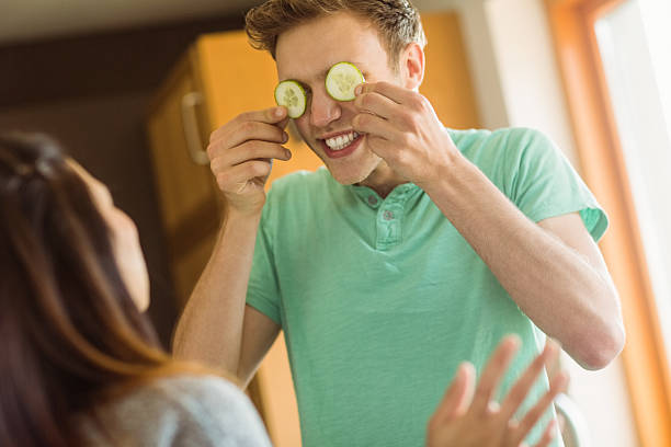 istock Cute man holding cucumber slices over eyes 518176143