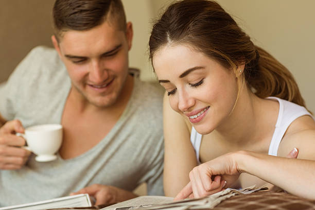 istock Cute couple reading newspaper in bed 518177073