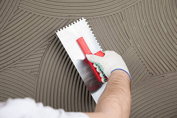 istock the worker applies glue for a tile on a wall 518180518