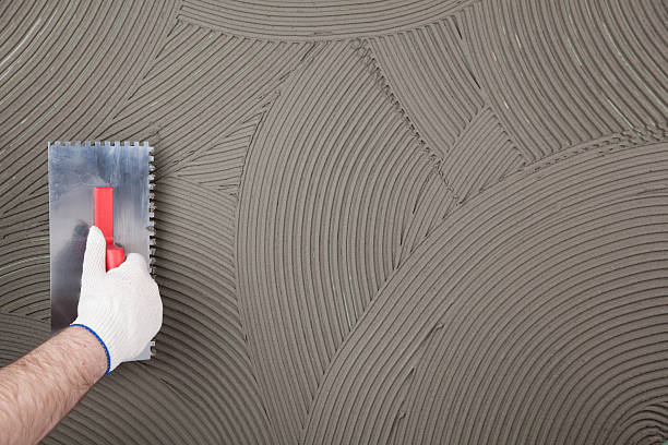 the worker applies glue for a tile on a wall