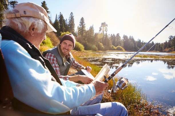 adulto pai e filho pescar à beira do lago, close-up - fishing active seniors family senior adult - fotografias e filmes do acervo