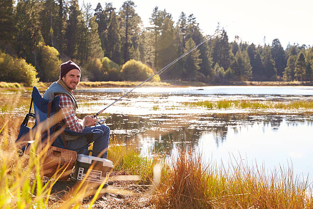 istock Man fishing by lakeside, looking to camera 518182706