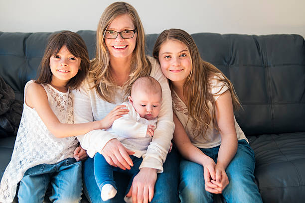 retrato de madre e hijas, sentado en un sofá en casa. - familia con tres hijos fotografías e imágenes de stock