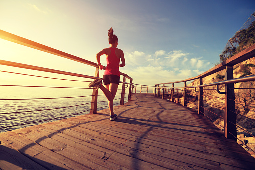young fitness woman running on seaside wooden boardwalk