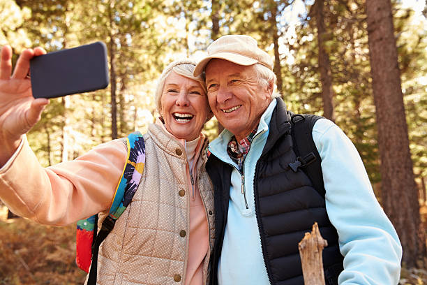 coppia senior sulla passeggiata in una foresta prendendo un selfie - bag senior adult outdoors friendship foto e immagini stock