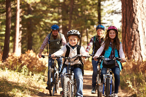 famiglia in montagna bike sul sentiero nella foresta, vista frontale - family with two children father clothing smiling foto e immagini stock