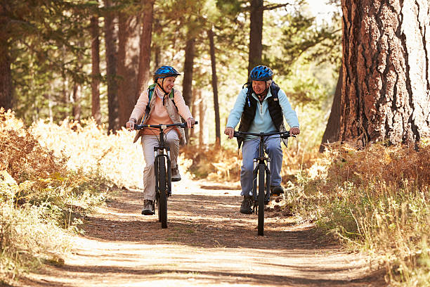 couple senior à vélo sur le sentier de montagne forêt, en californie - cycling senior adult sports helmet men photos et images de collection