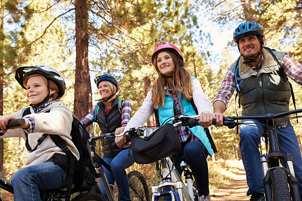 istock Family mountain biking in a forest, low angle front view 518185580