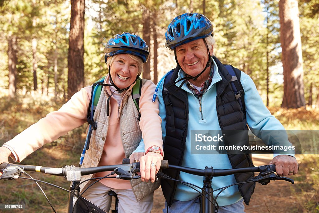 Senior pareja con Bicicletas de montaña en el bosque, retrato - Foto de stock de Andar en bicicleta libre de derechos