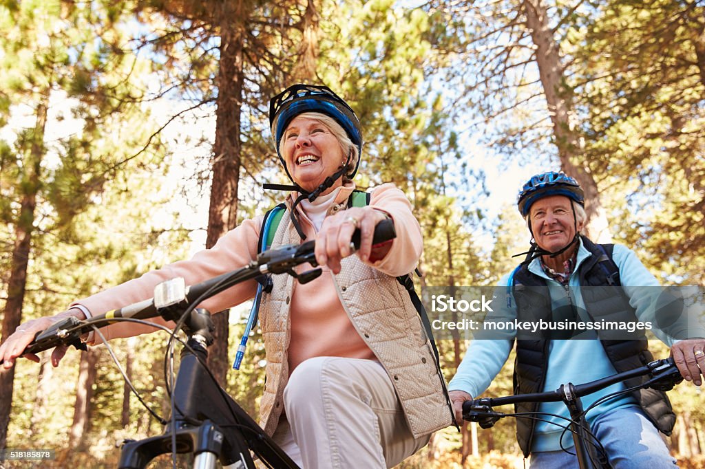 Senior couple mountain biking on a forest trail, low angle Cycling Stock Photo