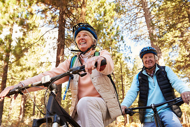 starszy mężczyzna i kobieta kolarstwo górskie w lesie szlak, niski kąt - cycling senior adult sports helmet men zdjęcia i obrazy z banku zdjęć