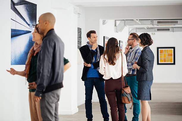 istock Visitors In Art Gallery Looking At Artwork And Talking 518198142