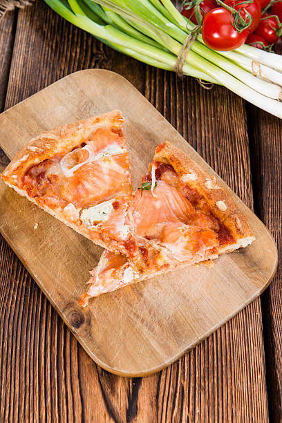 Homemade Salon Pizza on rustic wooden background (close-up shot)