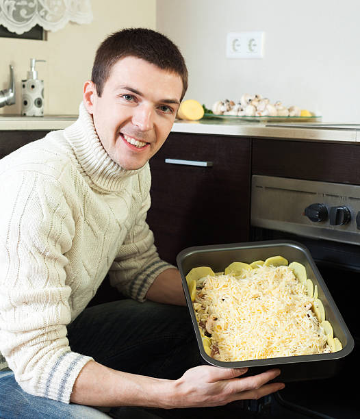 istock handsome  man cooking french-style meat. Adding grating cheese 518198581