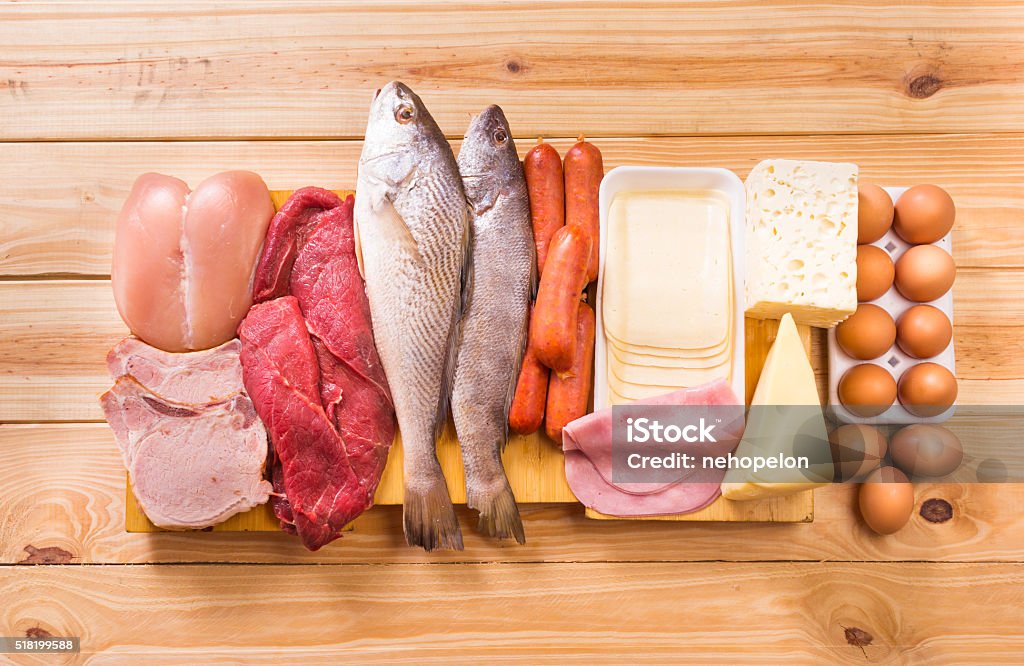 Food, Proteins Group of important proteins, meats, fish, dairy, eggs, white meat on a wooden table as background, Shot from above Fish Stock Photo