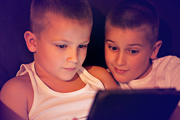 istock Brothers with an illuminated digital tablet tablet computer in the dark 518201385
