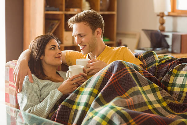 istock Young couple cuddling on the couch under blanket 518201563