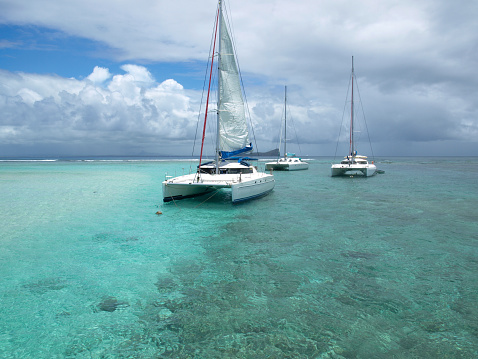 Three catamarans anchored in the turquoise blue water.