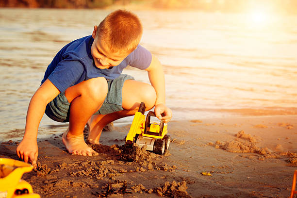 Boy playing on the beach with sand and toys